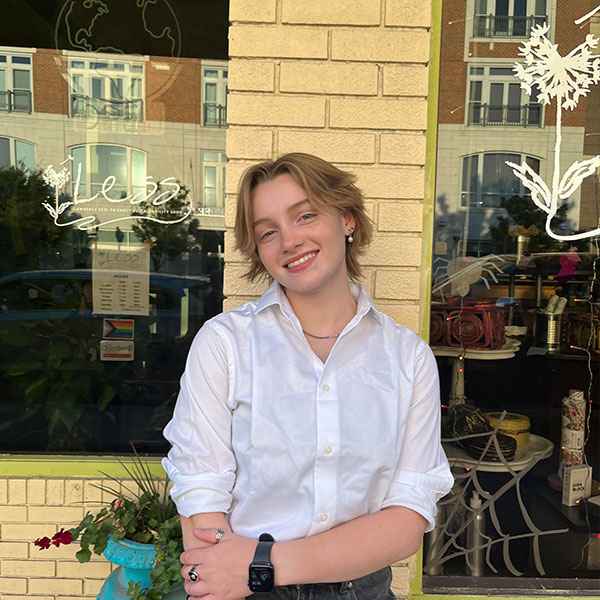 Young woman smiling in a white shirt in front of a café window.