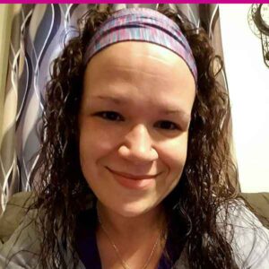 Woman with a headband smiling directly at the camera.